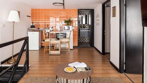 A modern kitchen with orange tiles, a dining area with a round table, and a refrigerator.