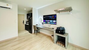 Un soggiorno moderno con televisione a schermo piatto montata a parete, un tavolino in legno, una scrivania con sedia e una dispensa a muro per le scarpe.