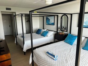 Una habitación de hotel con cama con dosel, una mesita de noche con lámpara y un cuadro en la pared.