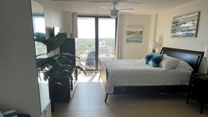 A bedroom with a bed, a nightstand, a ceiling fan, a window with a view, and a plant. - Anchorage 808 (Siesta Key)