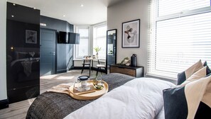 Une chambre à coucher moderne avec un lit, une table de chevet et un téléviseur fixé au mur.