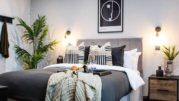 A modern bedroom with a grey bed, striped pillows, and a Bauhaus framed artwork on the wall.