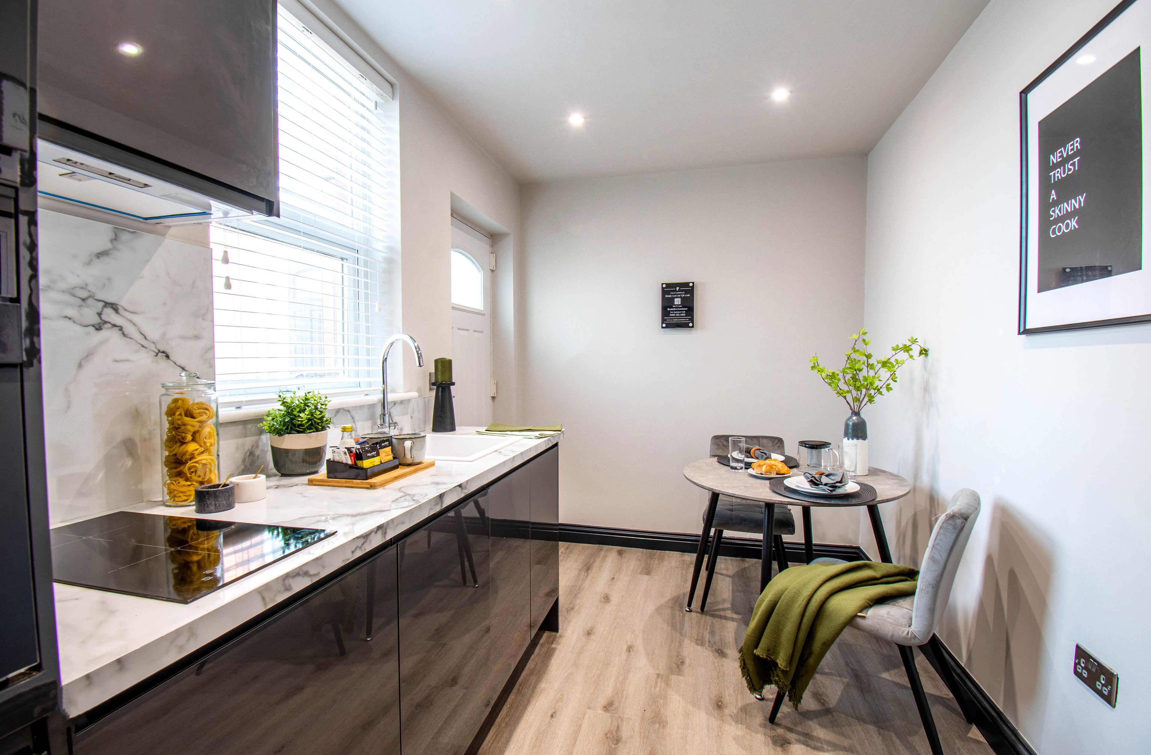 Une cuisine moderne dotée d’un plan de travail en marbre, d’un four encastré et d’un coin repas avec une table et des chaises.