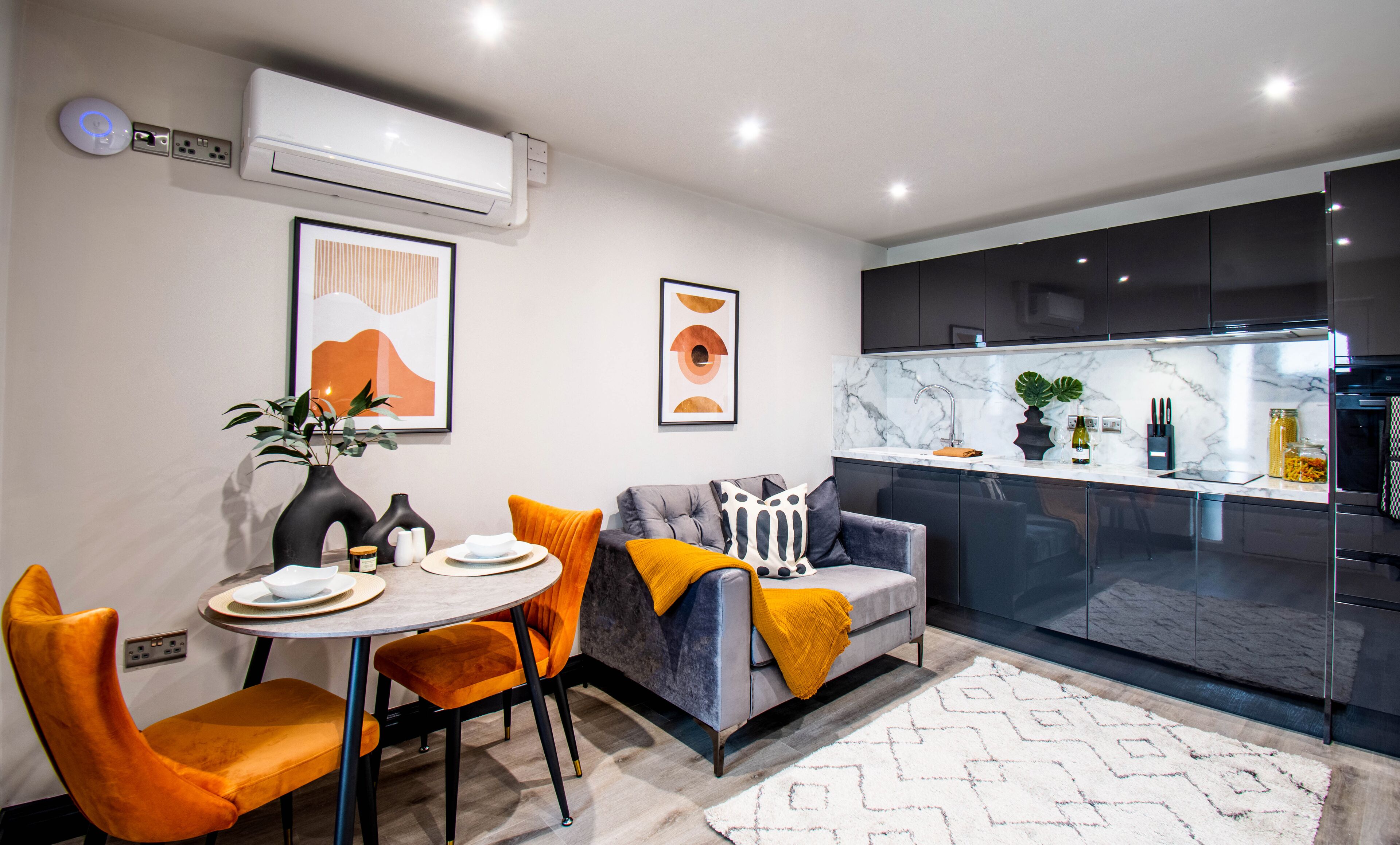 A modern kitchen with dark cabinets, a marble countertop, and a built-in oven.
