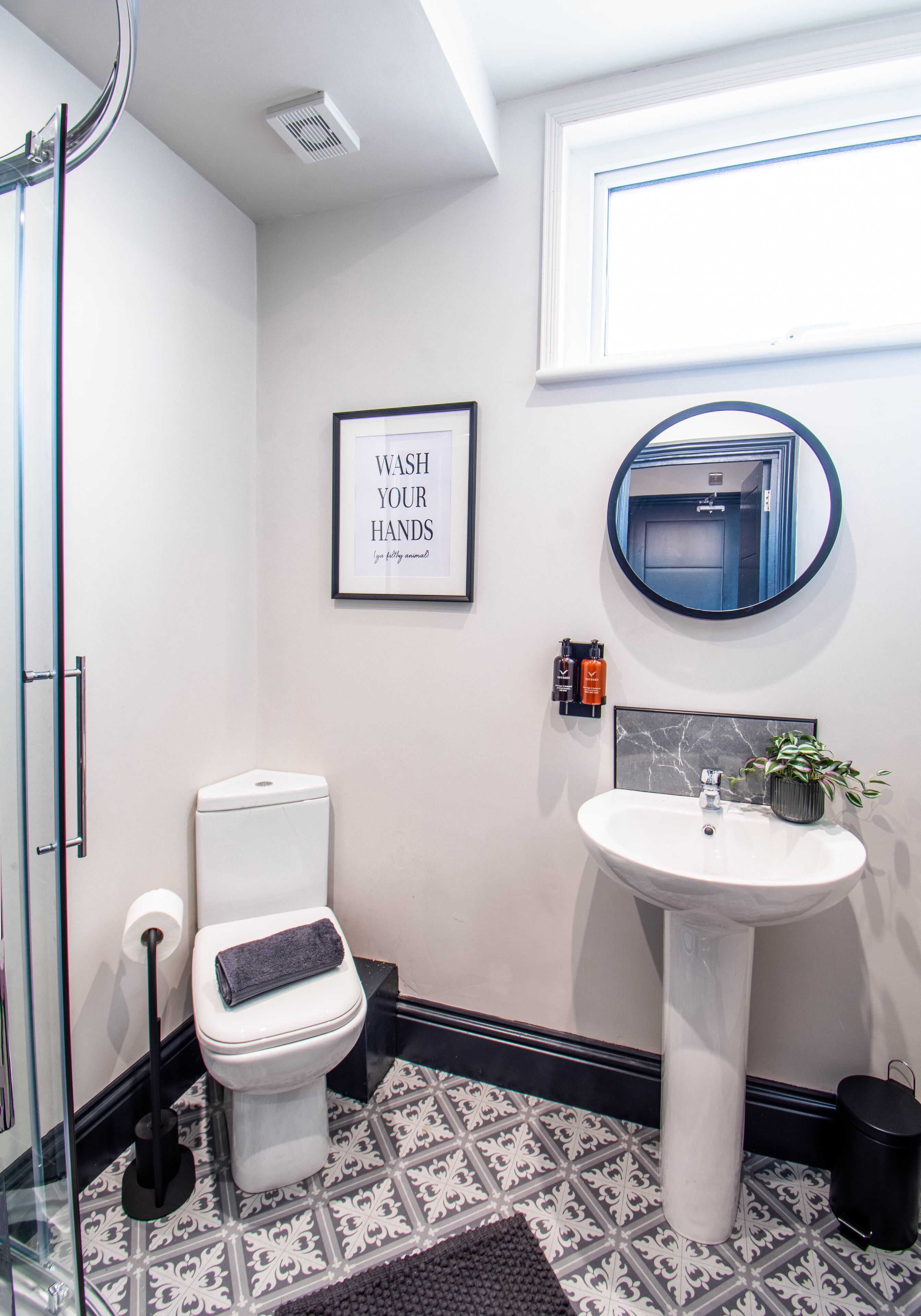 Een badkamer met toilet, wastafel en een bordje boven de wastafel.
