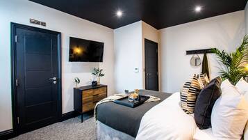 A modern bedroom with a bed, bedside table, TV, and a door.