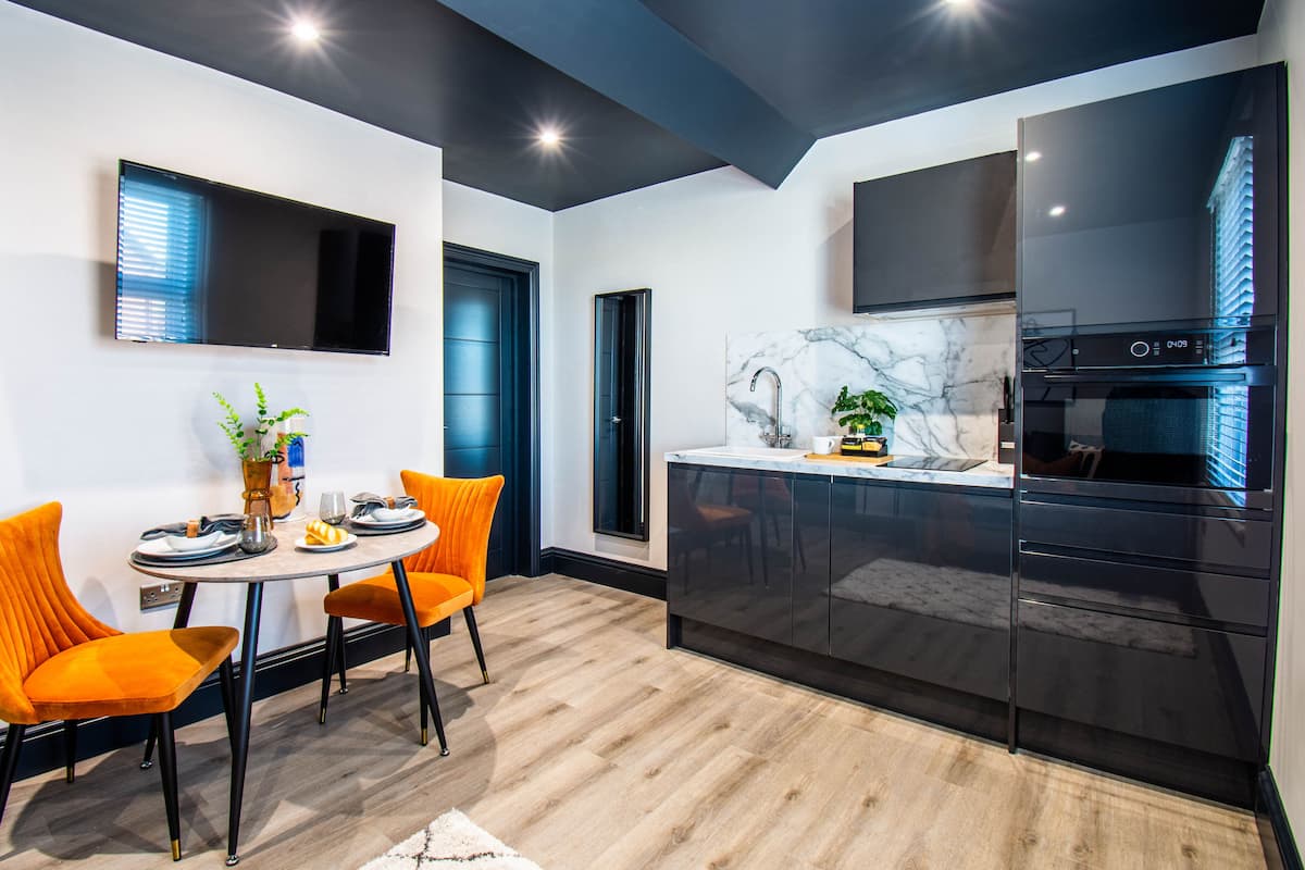 A modern kitchen with black cabinets, a marble countertop, and a built-in oven.