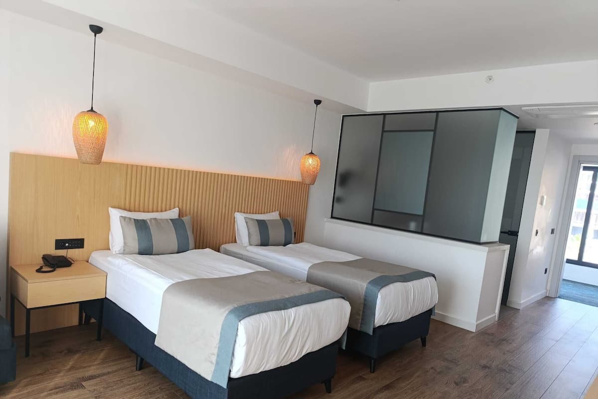 A hotel room with two beds, a nightstand, a phone, and a large mirror.
