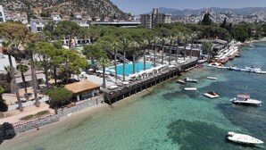 A coastal hotel with a pool, beach, and pier with boats. - Ömer Prime Holiday Resort (Kusadasi)