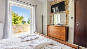 A bedroom with a large bed, a wooden dresser, a mirror, and a stone wall.