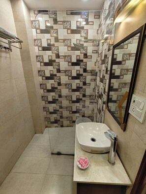 Un baño con pared de baldosas estampadas, un lavamanos blanco y un espejo.