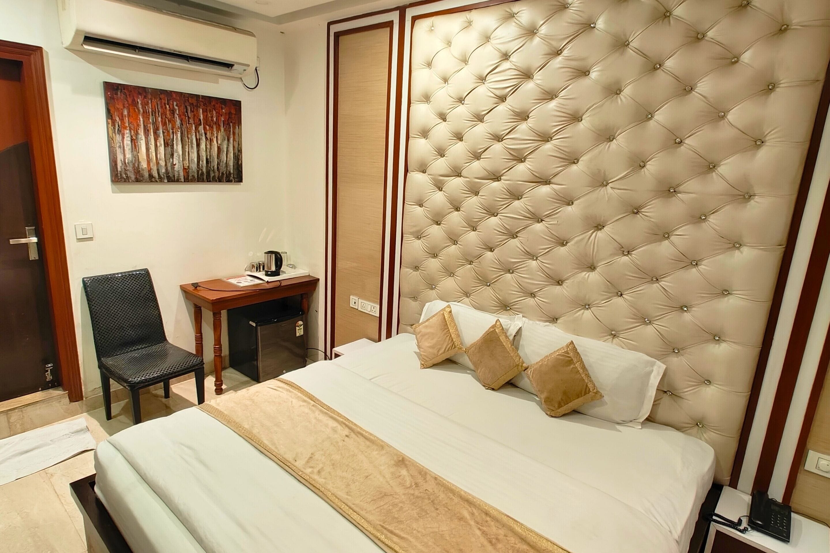 A hotel room with a large bed, a desk, and a chair.