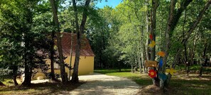 A rustic wooden cabin with a red roof, surrounded by dense green trees. - Cottage "Cocooning" (Saint-Chamassy)