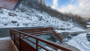 A snow-covered outdoor area with a wooden deck and a metal railing.