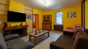 A living room with a fireplace, sofa, television, and wooden cabinets.