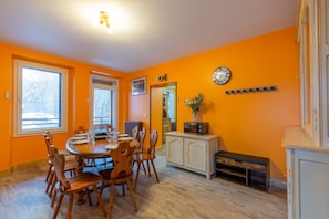 A dining area with a round table, chairs, a clock, and a cabinet.