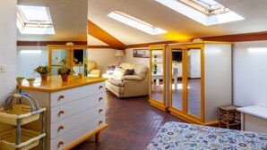 A bedroom with a skylight, a sofa, a bed, a dresser, and a small table. - Holiday Apartment "Loft parallela Lungomare posto auto" with A/C & Wi-Fi (Viareggio)