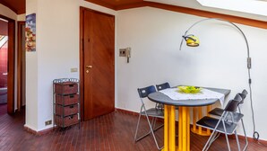 A dining area with a table, chairs, a lamp, and a wall-mounted light fixture. - Holiday Apartment "Loft parallela Lungomare posto auto" with A/C & Wi-Fi (Viareggio)