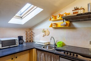 Una cucina con un lucernario, un forno a microonde, una moka, un lavandino e un fornello.