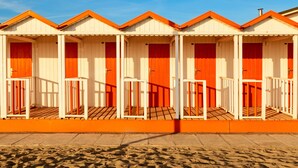 A row of beach huts with red doors and white railings, each with a small porch area. - Holiday Apartment "Loft parallela Lungomare posto auto" with A/C & Wi-Fi (Viareggio)