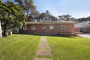 Een bakstenen huis met een verzorgd gazon en een pad van stenen dat naar de voordeur leidt.