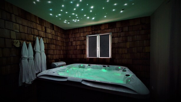 Ein Wellnessraum mit Whirlpool, Holzwänden und einem Fenster.