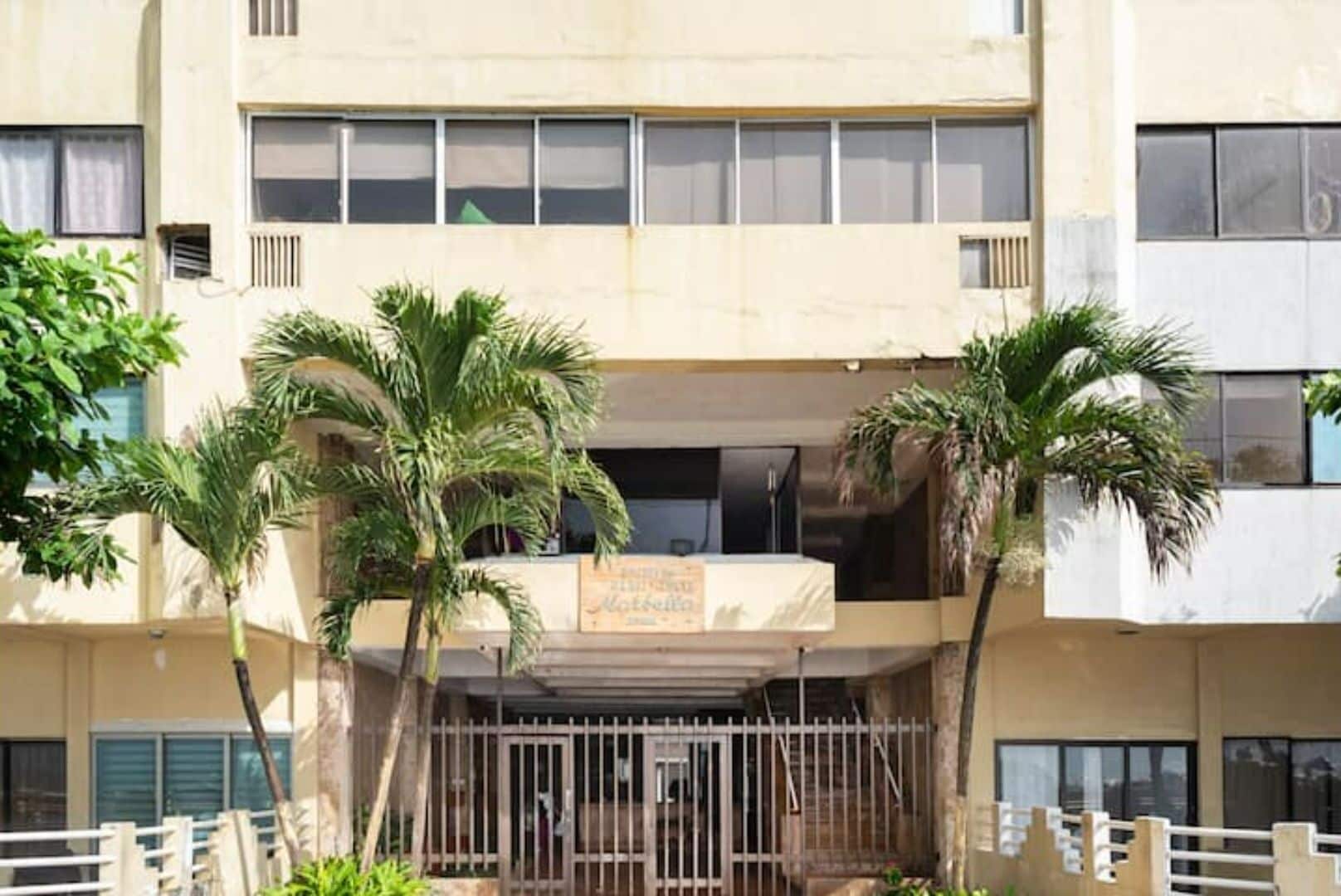 A multi-story building with a flat facade, large windows, and a gated entrance.