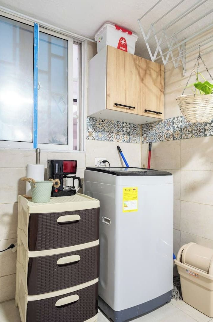 A compact kitchen with a refrigerator, a coffee maker, and a small cabinet.
