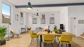 A modern living room with a dining area, large windows, and a fireplace.