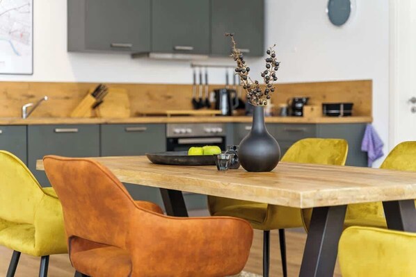 A modern kitchen with grey cabinets, a wooden countertop, and a vase with dried branches.