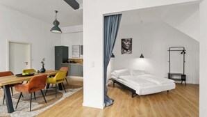 A modern apartment with a dining area, a bed, and a small kitchenette. - MEL&BENS Loft 2 | Terrace | Design | Weserstadion (Bremen)
