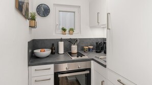 A modern kitchen with a built-in oven, a sink, and a window with two potted plants. - MEL&BENS Domshof | City center | Balcony | (Bremen)