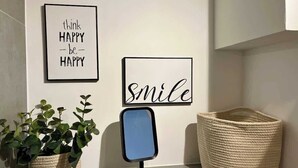 A wall with two framed motivational quotes, a potted plant, a mirror, and a woven basket. - MEL&BENS Domshof | City center | Balcony | (Bremen)
