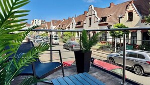 A balcony with a view of a street, a potted plant, and a table. - MEL&BENS Loft 1+2 for 8 P. | terrace | sauna | Design | Weserstadion (Bremen)