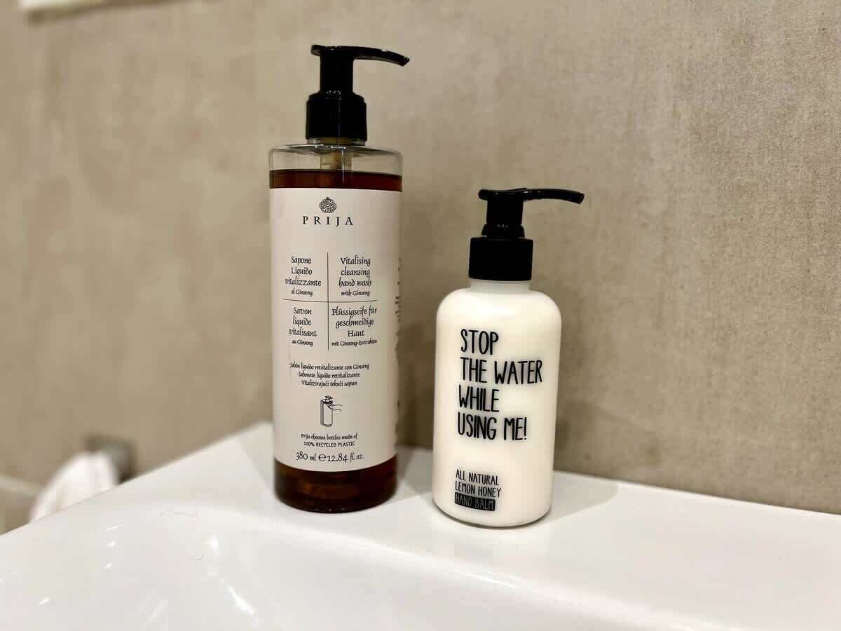 Deux flacons de produits pour les soins des mains sont posés sur le lavabo de la salle de bain.