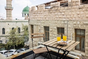 A balcony with a table, chairs, and a bowl of cereal with orange juice.