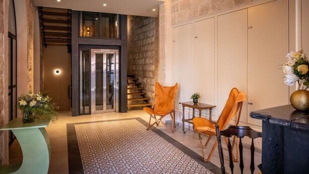 Interior moderno com escada, área de estar e balcão de recepção.