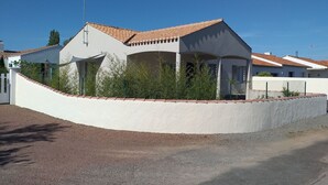 A modern house with a curved roof, a white exterior, and a gravel driveway. - Charming 6-Person Cottage Near Ocean & Cycling Routes (Beauvoir-sur-Mer)