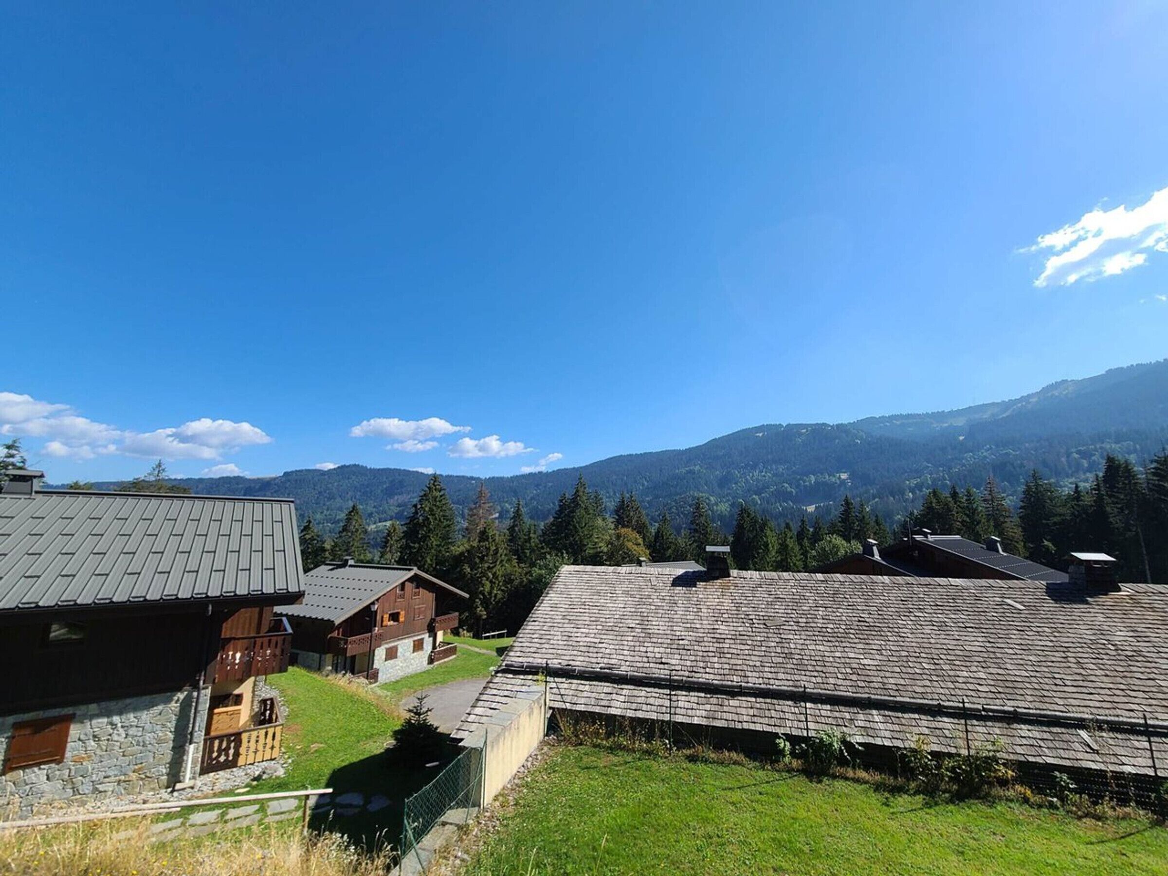 A rural setting with traditional wooden houses, a clear sky, and a mountainous backdrop.