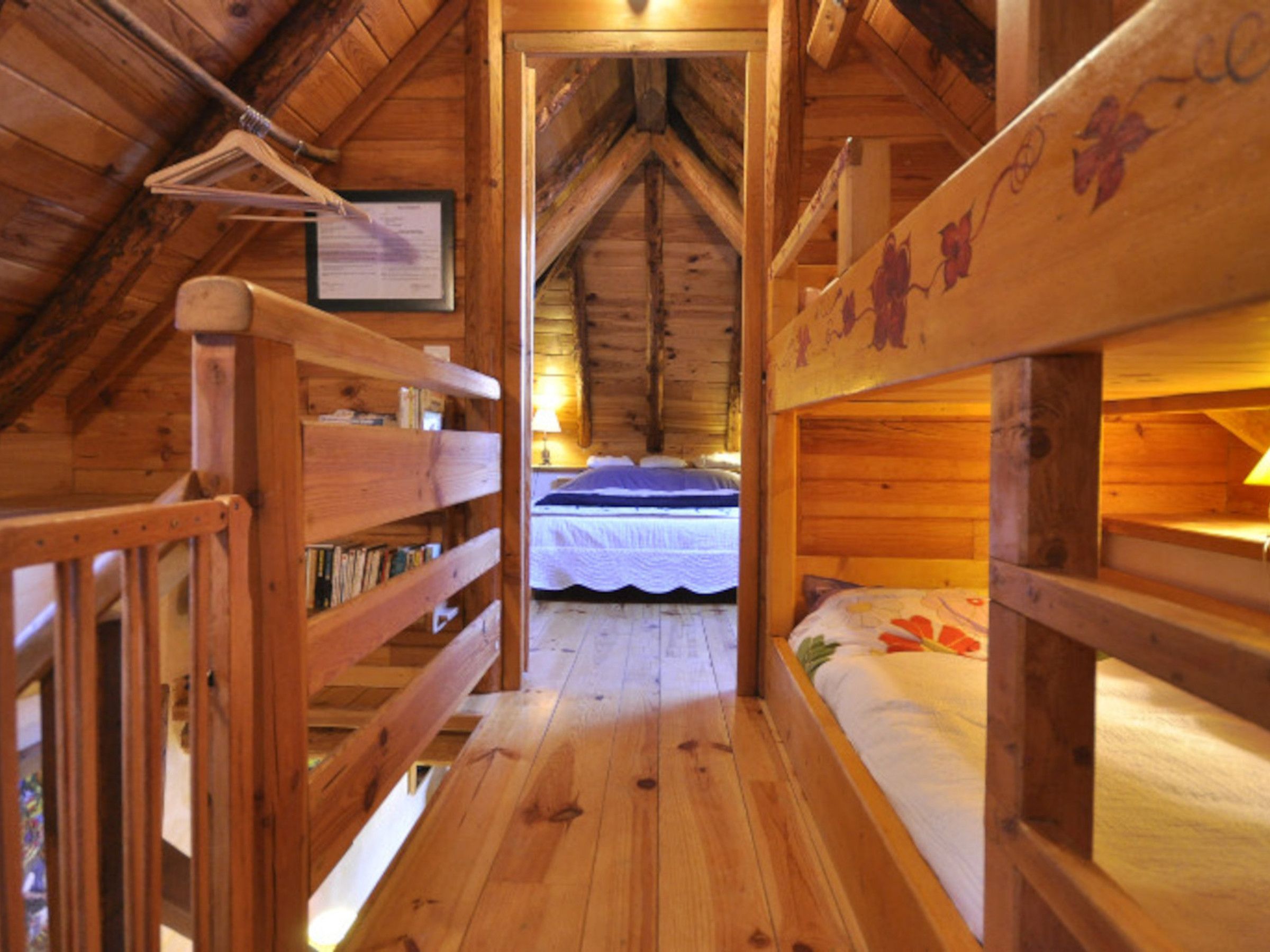 Una baita di legno con letti a castello, un certificato incorniciato al muro e un pavimento in legno.