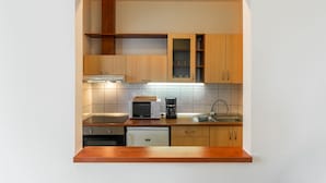 A compact kitchen with wooden cabinets, a microwave, a coffee maker, and a dishwasher. - Holdvirág Hotel (Sarvar)