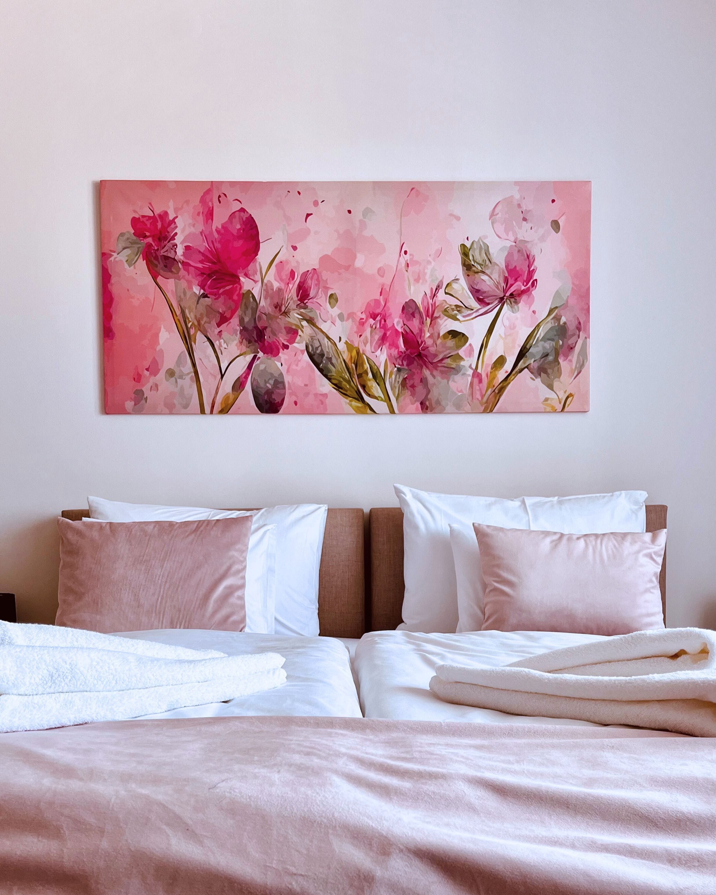 A bedroom with a bed, pillows, and a large floral artwork on the wall.