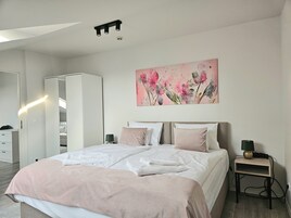 Un dormitorio moderno con una cama grande, mesitas de noche, un armario y un cuadro en la pared.