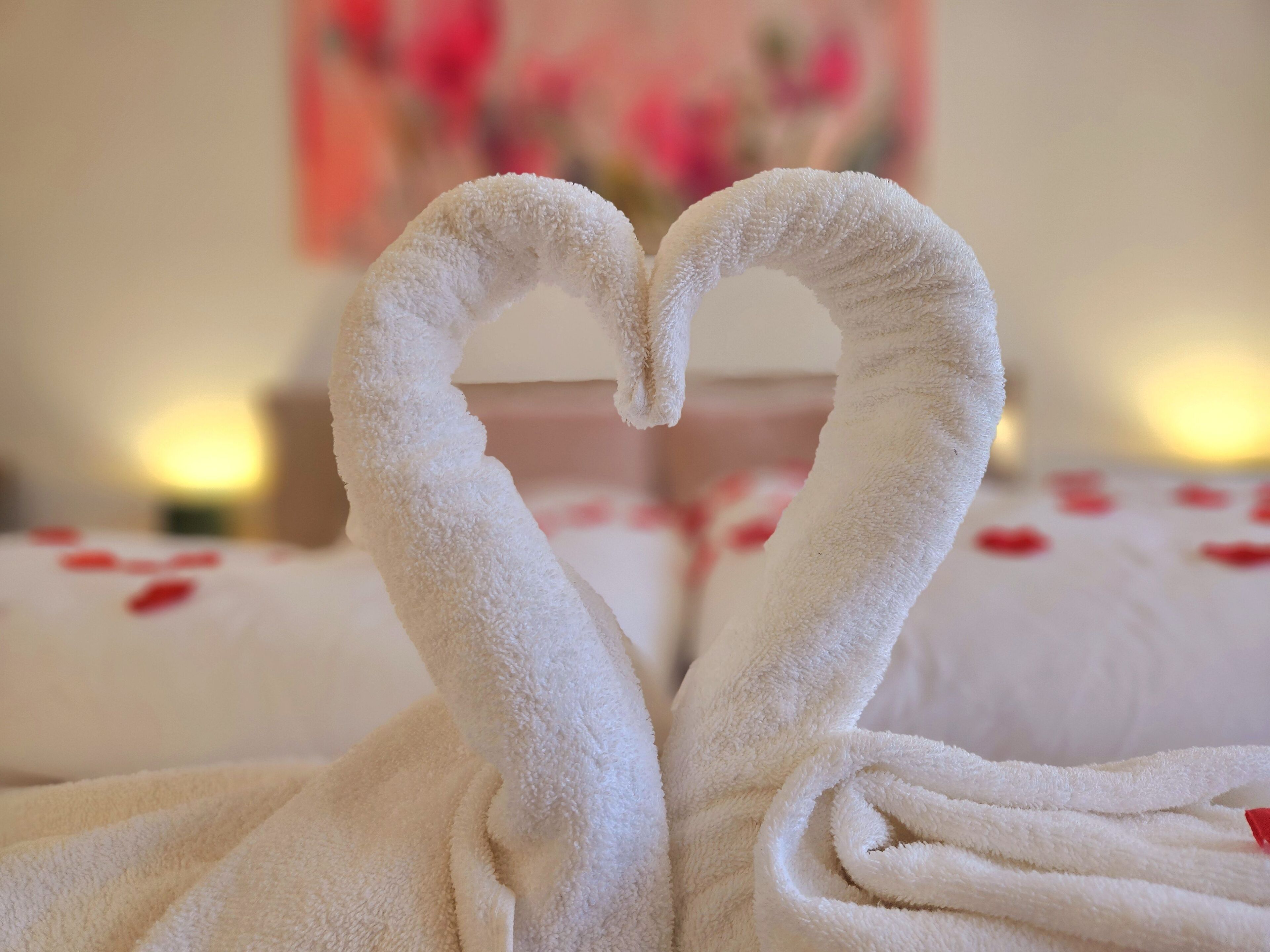 A bed with white towels arranged in a heart shape.