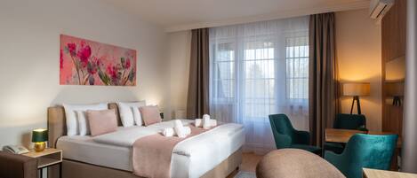 A hotel room with a bed, a desk, a chair, a lamp, and a painting on the wall.