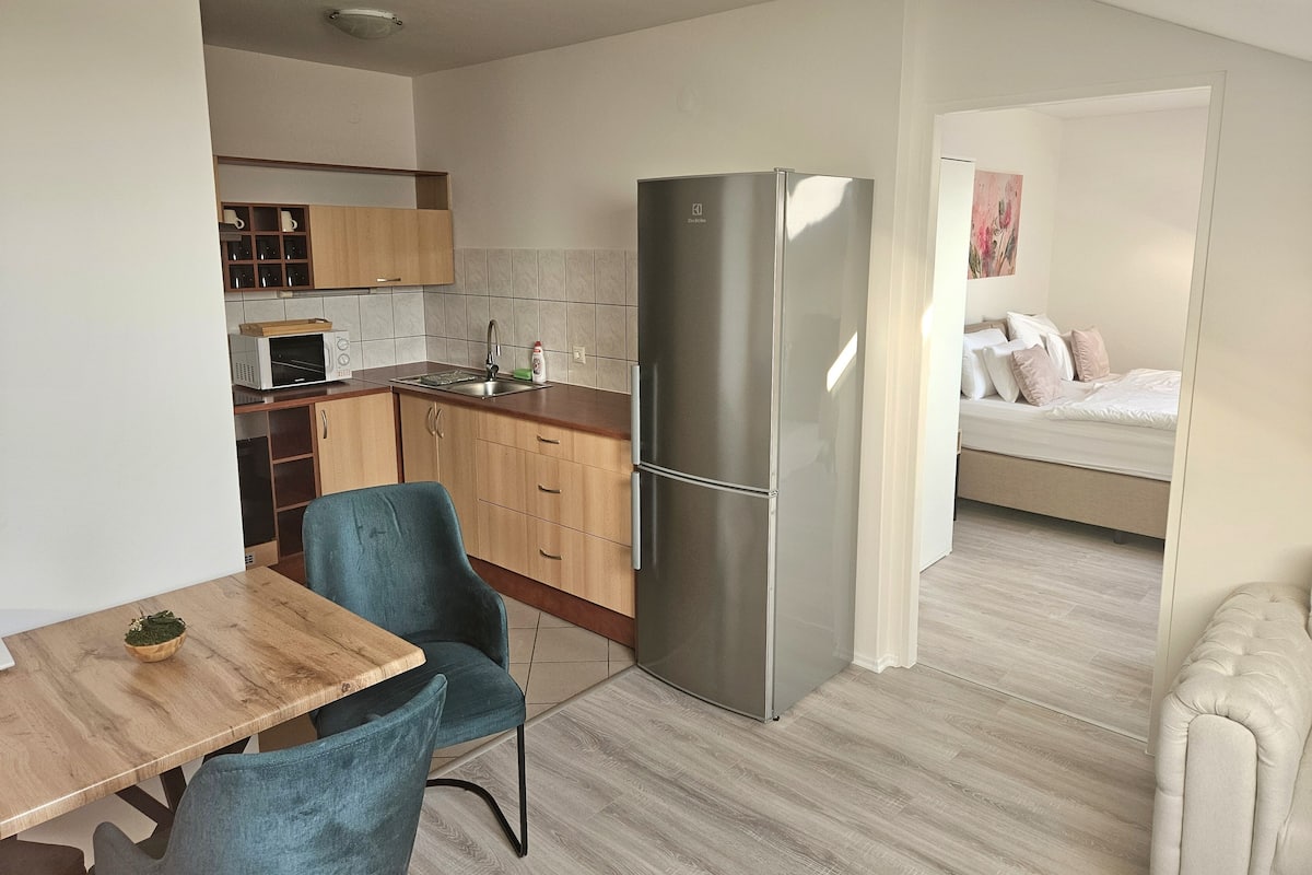 A compact kitchen with a refrigerator, microwave, and wooden cabinets.