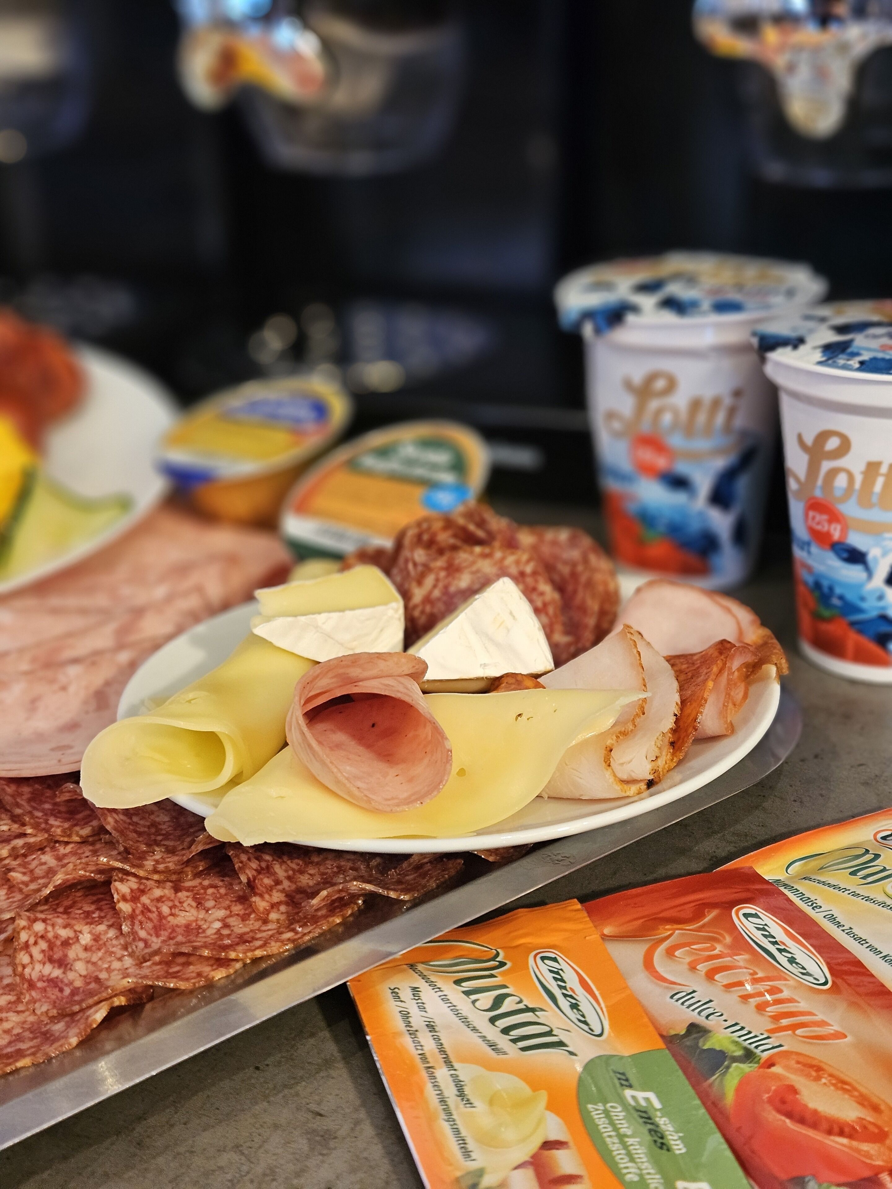 A variety of food items including sliced meats, cheeses, and packaged goods on a table.