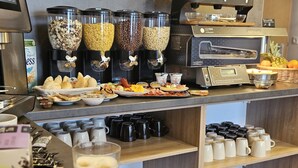 A breakfast buffet with various food items, coffee machines, and coffee cups. - Holdvirág Hotel (Sarvar)