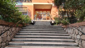Eine Treppe führt zu einem Gebäudeeingang mit Steinwänden und Metallgeländern.
