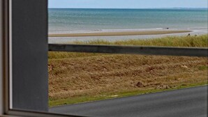 A view of a beach with a road in the foreground and a clear sky. - Family house near the beach (Saint-Marcouf)